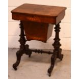 A late Victorian inlaid walnut sewing table raised on four carved supports with turned