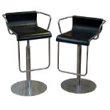 A pair of chromed and faux leather swivel bar stools with circular central columns and circular