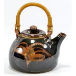 LOWERDOWN POTTERY; a stoneware teapot with cane handle, foxglove decoration on tenmoku ground,