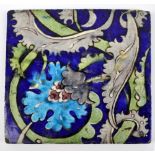 WILLIAM DE MORGAN; a large square sectioned tile painted with a turquoise stylised flower,