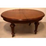 A 19th century wind-out oval dining table with two panels, on baluster supports and castors,