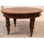 A Victorian oak circular wind-out D-end dining table with four additional leaves,