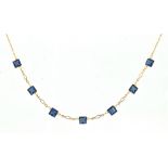 A 9ct yellow gold link necklace with seven square cut blue stones, each flanked by two faux pearls,