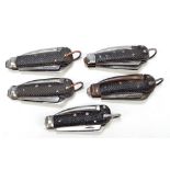 Five military issue clasp knives with checkered black bodies, hinged spike and two blades,