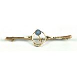 A 9ct yellow gold bar brooch, set with a single round cut blue stone within a floral motif,