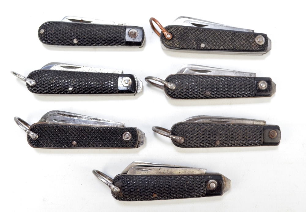 Seven similar checkered black bodied twin bladed pocket knives, six with ring loop attachments (7).