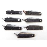 Seven similar checkered black bodied twin bladed pocket knives, six with ring loop attachments (7).