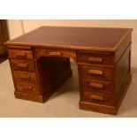 A c1930s oak kneehole desk, one central drawer with four drawers to either side on a plinth base.