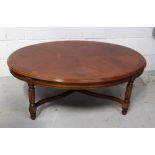 A reproduction mahogany oval coffee table on reeded supports to claw feet and cross-stretcher,