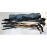 A collection of vintage golf clubs, some hickory-shafted, in a blue carry bag.