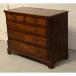 An early 19th century oak and mahogany cross-banded chest of two short and three long drawers on