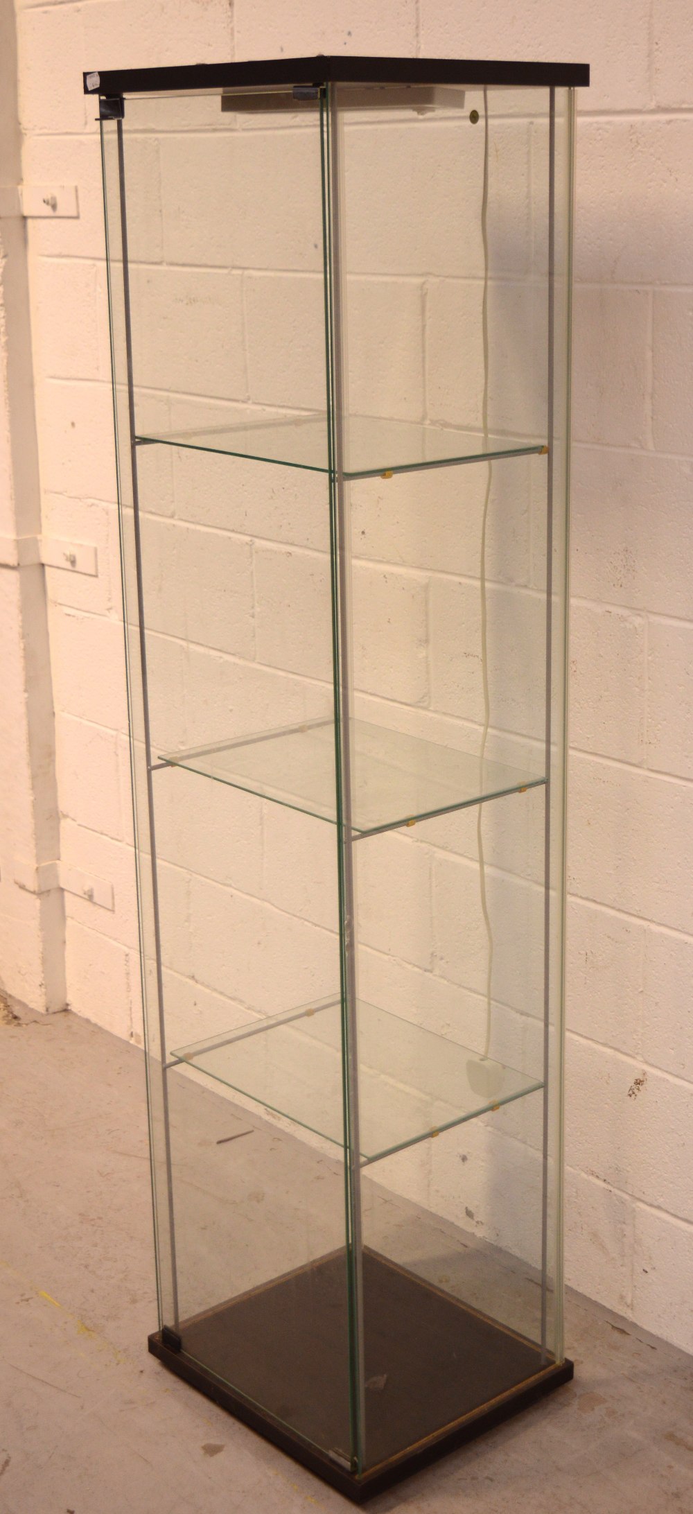 A modern single-door glazed display cabinet with three glass shelves and electric light fitting,