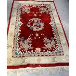 A red ground wool Oriental rug with dragon decoration, 201 x 120cm.