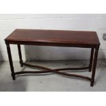 A reproduction mahogany hall table on reeded supports and cross-stretchers,