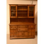 An Ercol dresser with shelves and glazed door above a base with arrangement of drawers and doors,