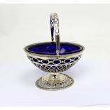 A hallmarked silver swing-handled basket with blue glass liner, London date mark rubbed,