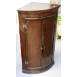 A George III oak two-door bow-fronted corner cupboard with engraved brass hinges.