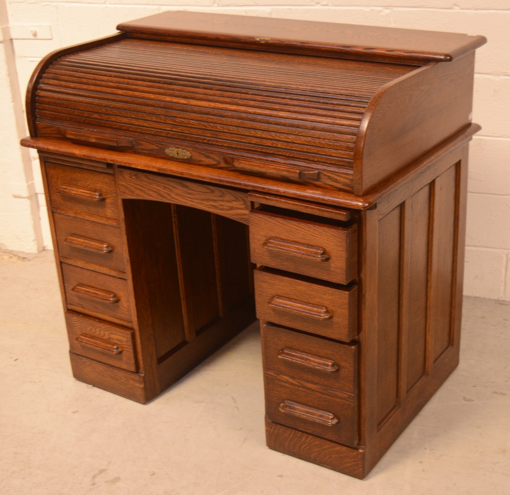 An early 20th century oak roll-top pedestal desk,