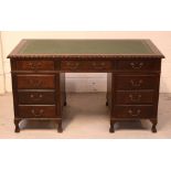 A mid-20th century mahogany kneehole desk with green faux leather insert,