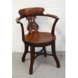 A late 19th/early 20th century elm elbow chair with circular seat panel and pierced backrest,