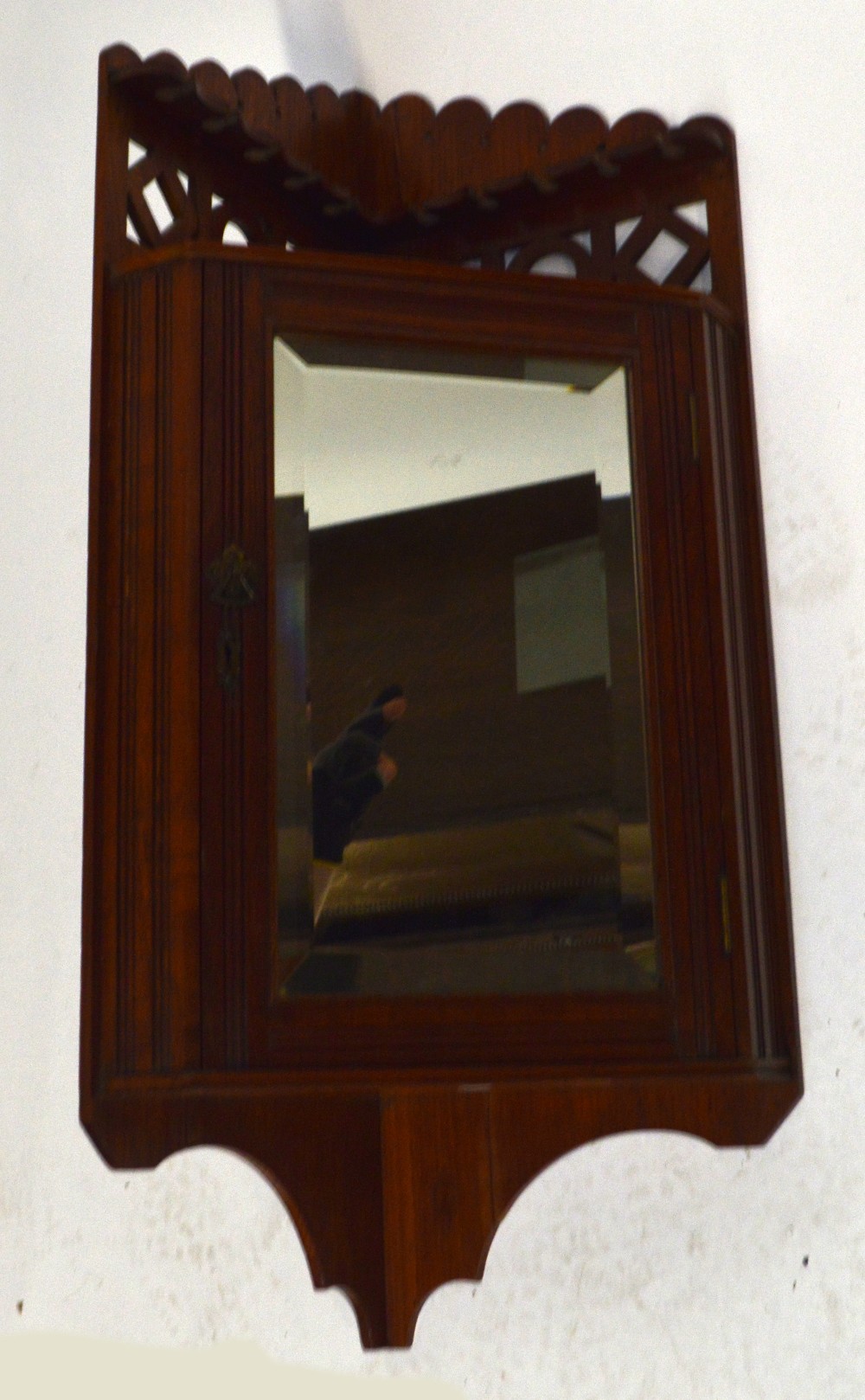 An Edwardian oak corner smoker's cabinet with pipe rack above single mirrored door enclosing two