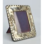 An Elizabeth II hallmarked silver rectangular photograph frame, embossed with cherubic figures,