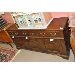 A reproduction oak sideboard with three drawers above three cupboard doors, on bracket feet,