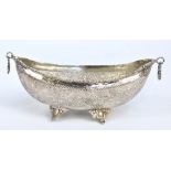 A circa 1900 Persian white metal boat shaped bowl with twin ring handles, on four cast supports,