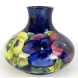 MOORCROFT; a 'Pansy' pattern tubeline decorated squat bottle vase,