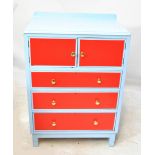 A blue and red painted tallboy with two cupboard doors above three drawers raised on block feet,