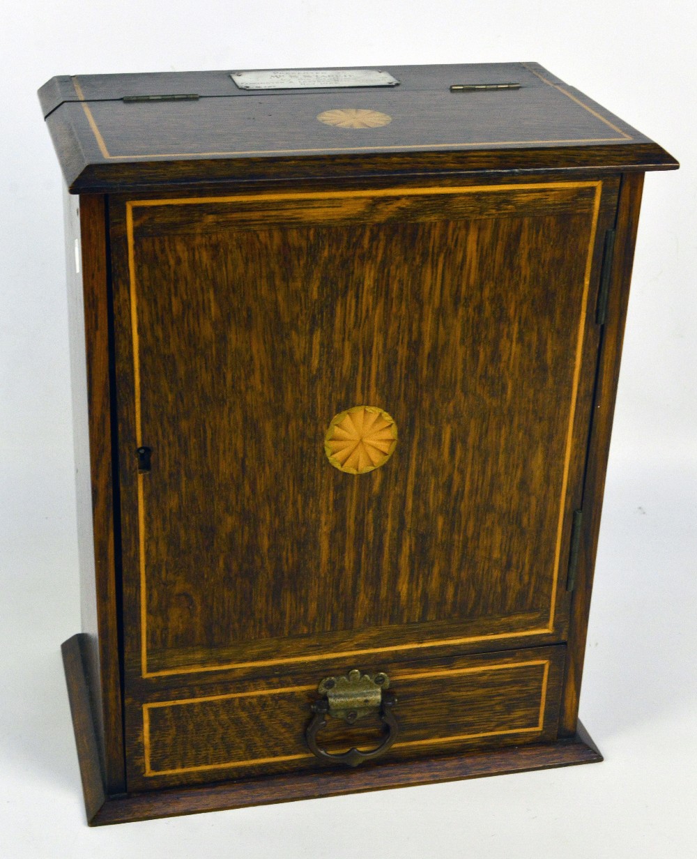 An early 20th century oak and inlaid smoker's compendium, with cupboard door beneath hinged lid,