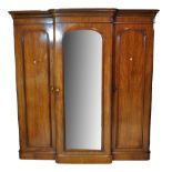 A Victorian mahogany breakfront triple wardrobe with moulded cornice above central mirrored door