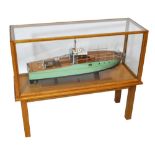 A large wooden model of a motor launch with green painted hull and detailed accessories,