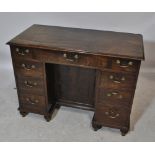 A late George III mahogany kneehole desk with three frieze and six pedestal drawers around a