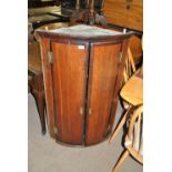 A George III oak and mahogany crossbanded two door wall hanging bowfronted corner cupboard,