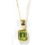 A 9ct yellow gold and green peridot rounded rectangular pendant supported on a fine link chain.