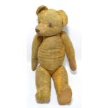 An early 20th century straw filled teddy bear with stitched nose and mouth and with glass eyes,