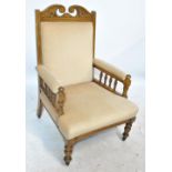 A late Victorian oak cream upholstered armchair, on turned front legs to castors.