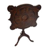 A George III Irish mahogany tilt-top games table, carved with foliate motifs to the top,