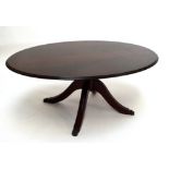 A reproduction mahogany oval coffee table with four outswept legs to brass paw feet, width 121cm.