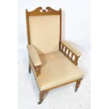 A late Victorian oak cream upholstered armchair, on turned front legs to castors.