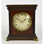 An early 20th century amboyna mantel clock of small dimensions with relief pediment and plinth and