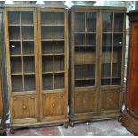 A pair of early 20th century oak bookcases with moulded cornices above twin glazed doors enclosing