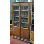 An early 20th century oak bookcase with moulded cornice above twin glazed doors enclosing three