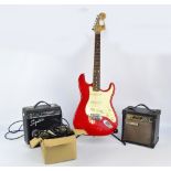 A red Squier Stratocaster, serial no.CY99118161, with two amps and a quantity of cables.