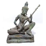 A circa 1900 Indian bronze figure of a seated deity playing a tanpura, on rectangular base,