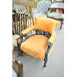 A late Victorian ebonised upholstered tub chair on cabriole legs.