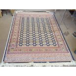 A blue ground Bokhara carpet decorated with geometrical motifs within an ornamental border,