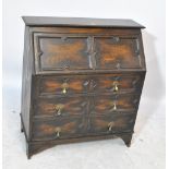 An early 20th century oak bureau with fall-front enclosing fitted interior above three long drawers,