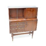 A 1960s walnut side cabinet with twin sliding glazed doors beside a hinged cupboard door above